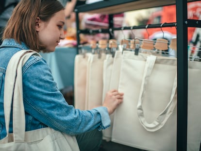 Una mujer compra bolsas de tela en un mercado.