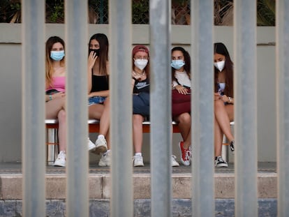 Jóvenes con mascarillas esperan el tren en Canet de Mar (Barcelona), en el verano de 2021.