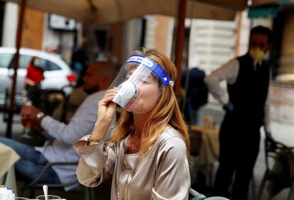 Una mujer se toma una taza de café en la terraza de un bar en Roma (Italia).