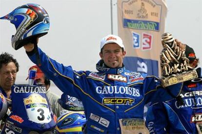 El piloto francés Cyril Després alza sonriente el trofeo logrado en la edición 2005 del rally Dakar.