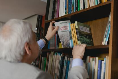 El politólogo eligiendo un volumen de su biblioteca.