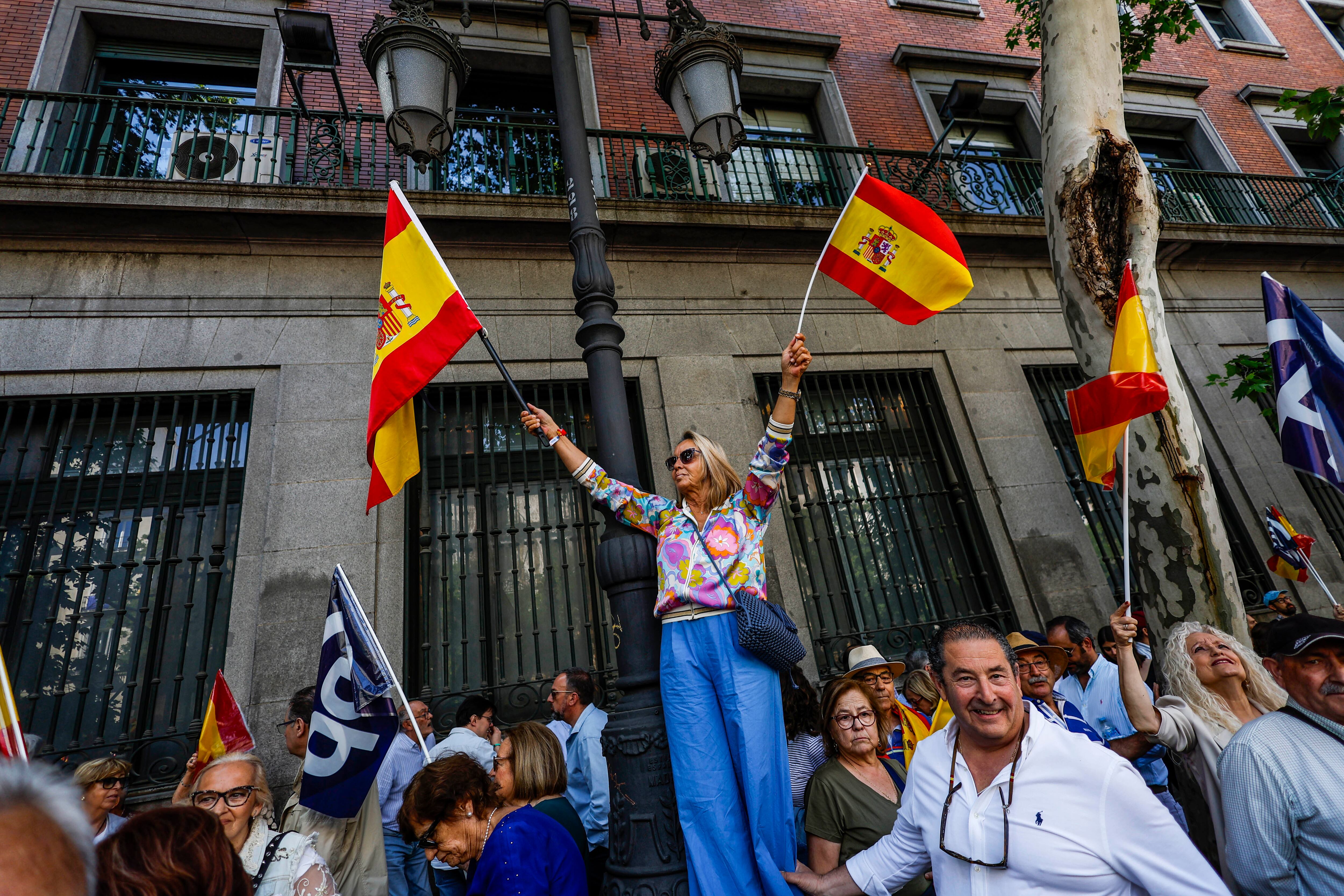 Una simpatizante del Partido Popular ondea dos banderas de España en las inmediaciones de la plaza de la Independencia de Madrid, durante la protesta, este domingo.