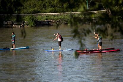 Tres ciudadanos practican paddle surf a primera hora de este sábado en Zaragoza. 