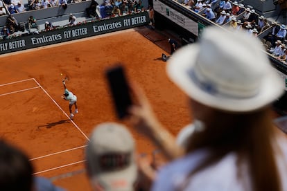 Una mujer fotografía el partido de semifinales entre Alcaraz y Djokovic desde las gradas.