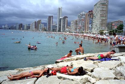 Tourists sunbathing on the rocks in Benidorm.