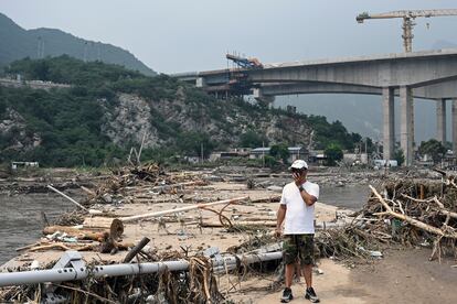 Un hombre camina junto a un puente afectado por las inundaciones en Pekín, el jueves.