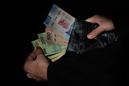 Un ciudadano saca muestra los pesos mexicanos que lleva en su cartera