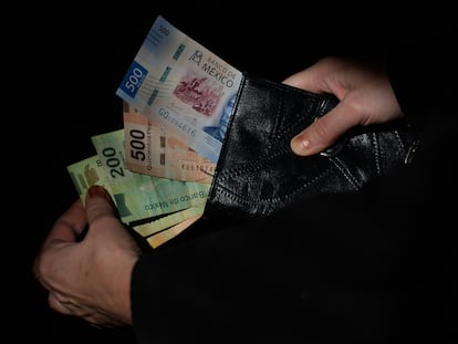 Un ciudadano saca muestra los pesos mexicanos que lleva en su cartera