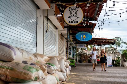 Turistas caminan frente a un local protegido con sacos de arena ante la inminente llegada del huracán 'Lidia' a Puerto Vallarta, este 10 de octubre.