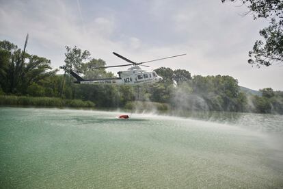 Un helicóptero trabaja este jueves para aplacar las llamas del incendio forestal declarado en la Sierra de Leyre. Según ha informado el Gobierno de Navarra, los medios aéreos harán descargas sobre los lugares donde persisten las llamas mientras se vigila el perímetro, prácticamente estabilizado.