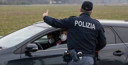 Un policía italiano habla con un conductor en los alrededores de Casalpusterlengo, una de las localidades conde las autoridades han decretado la cuarentena.  