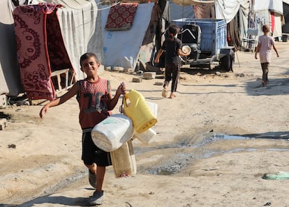 Un niño palestino carga envases para llenarlos de agua, en Deir al-Balah, este lunes.