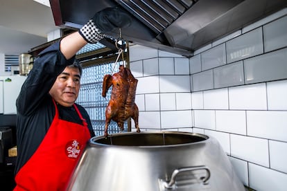 Miguel Chong saca un pato asado del horno vertical.