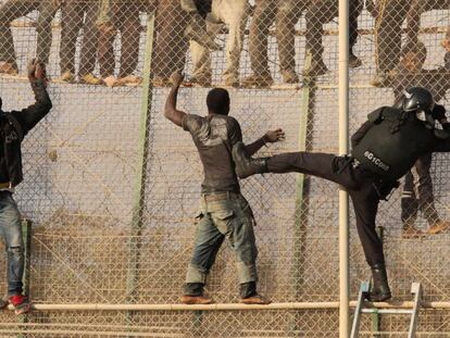 Un grupo de inmigrantes subsaharianos se enfrenta a un polic&iacute;a tras saltar la valla de Melilla.