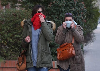 Two women cover their mouths on a street in Igualada.
