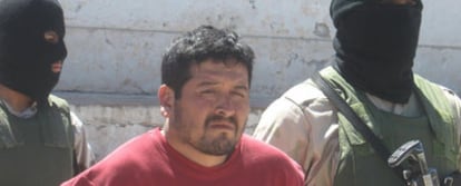 Dos agentes mexicanos enmascarados llevan detenido a un narcotraficante en Sonora.