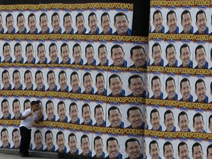 Un niño pasa junto a una pared llena de carteles electorales de Chávez.
