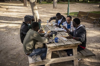En la foto, varios refugiados comen en el parque La Fiesta del Árbol después de jugar al futbol.