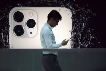 FILE PHOTO: A man walks next to an advertisement for Apple's new iPhone 11 Pro at the Apple Store in IFC, Central district, Hong Kong, China