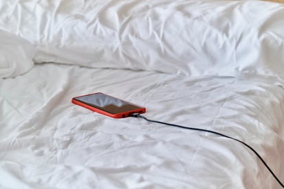 Un teléfono móvil cargando sobre una cama.