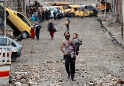 Las fuerzas iraquíes liberan Mosul tras una larga batalla de 10 meses que deja miles de civiles muertos, más de 800,000 desplazados y la segunda ciudad de Irak destruida. En la imagen, un hombre huye el sábado con su hija de la parte de Mosul controlada por el Estado Islámico, en 2017.