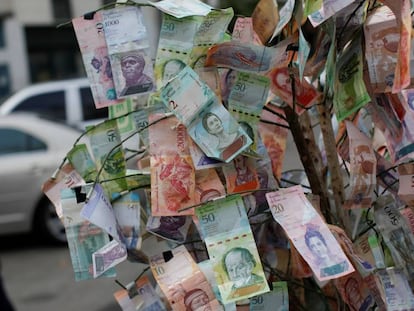 Un hombre pasa frente a billetes de bolívar tendidos en una calle de Caracas.