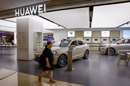 A woman walks next to a Huawei AITO M5 SUV at a showroom in Beijing, China, 10 August 2023 (issued 11 August 2023).