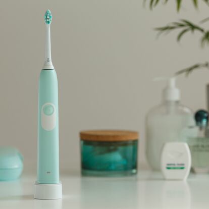 Un cepillo de dientes sobre un cargador inalámbrico en una imagen rodeado en segundo plano por otros elementos de higiene personal