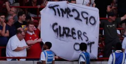 Un aficionado del Manchester United sostiene una pancarta contra la familia Glazer. AFP