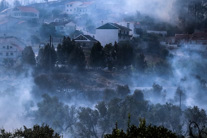 El Instituto del Mar y de la Atmósfera ha declarado para este lunes la alerta naranja por altas temperaturas en 8 de los 18 distritos del país y prevé un agravamiento para el martes, cuando todos pasen a estar en alerta naranja, a excepción del Algarve. El organismo prevé que las altas temperaturas continuarán hasta el final de la semana. En la foto, el humo cubre la localidad de Caneças, a las afueras de Lisboa.  