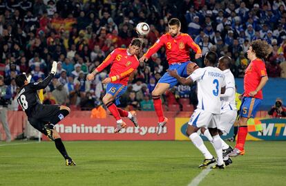 Sergio Ramos y Gerar Piqué saltan a por un balón al tiempo que el portero hondureño Noel Valladares intenta atajarlo.