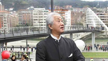 El arquitecto japonés Arata Isozaki, delante del paso elevado que diseñó para conectar la pasarela de Calatrava (al fondo) a Uribitarte en Bilbao, en 2019.