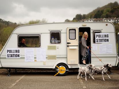Una mujer sale con sus perros de una caravana convertida en colegio electoral en Cornualles, al sureste de Inglaterra.