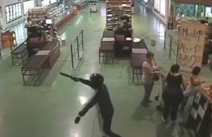 Uno de los atracadores apunta con una escopeta recortada en uno de los asadores de pollos que asaltaban.