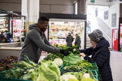 Tony trabaja en el Mercado de Trieste atendiendo el puesto de frutas y verduras de Barikama. En la imagen, empaqueta el pedido que acaba de comprar una clienta.