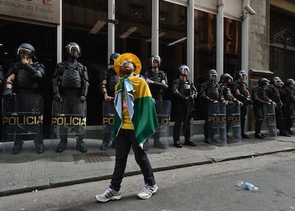 Menino com a bandeira do Brasil amarrada do pescoço passa em frente aos policiais, no centro de São Paulo. A greve dos metroviários, em seu quinto dia, conta com o apoio do Movimento dos Trabalhadores Sem Teto (MTST) e de outros sindicatos.