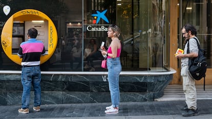 Clientes en una cajero de CaixaBank.