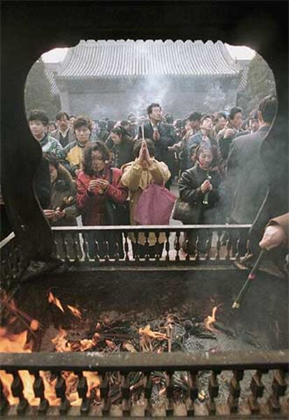 Un grupo de chinos ora y quema incienso en un templo de Pekín con motivo del nuevo año lunar.