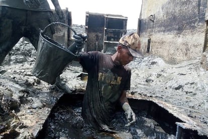 Shipbreaking workers clearing sludge from a ship