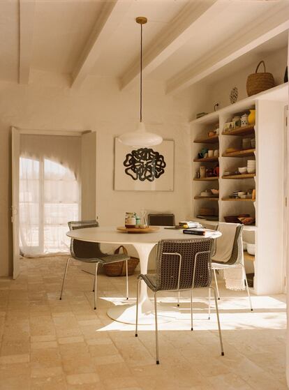 En el comedor, la mesa es el modelo Tulip, de Eero Saarinen; las sillas, regalo de la madre de Lumbreras; la lámpara, de Zangra, y las estanterías son del mismo artesano que realizó la bóveda de la cocina. Al fondo, dibujo de Alejandra Rein.