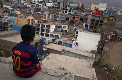 Criança com a camiseta de Messi observa um trabalhador que dedetiza o cemitério Mártires 19 de Julio, em Lima, no Peru, para evitar a proliferação do vírus do dengue, o chikungunya e Zika.