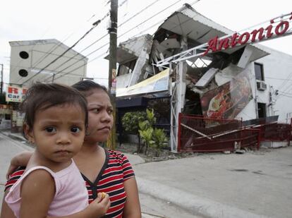 Una mujer y un ni&ntilde;o junto a una casa destrozada por el se&iacute;smo  en Ceb&uacute;.