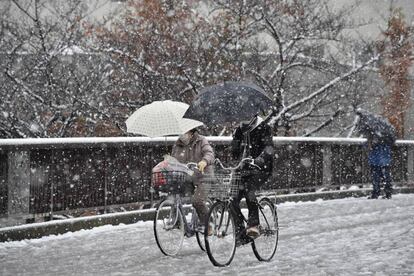 Una pareja monta en bicicleta con paraguas en un día de nieve de Tokio (Japón).