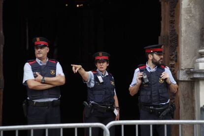 Tres 'mossos' de pie en la entrada del Palau de la Generalitat, en Barcelona, este sábado. El frente del edificio se encuentra vallado.