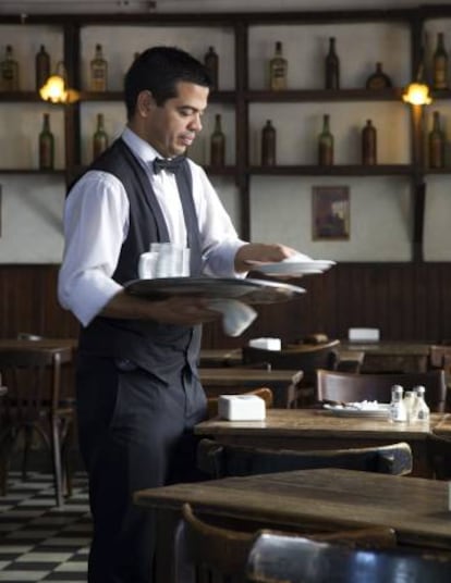 Mobiliario de madera y piso ajedrezado en el café Plaza Dorrego, en el barrio porteño de San Telmo.