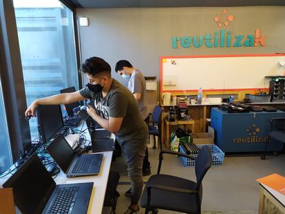 Dos jóvenes en el taller de reparación de aparatos informáticos de ReutilizaK en Madrid.