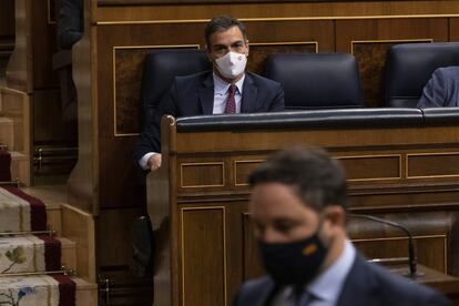 El presidente del Gobierno, Pedro Sánchez, sentado en su escaño, observa al líder de Vox, Santiago Abascal, este jueves en el Congreso. 