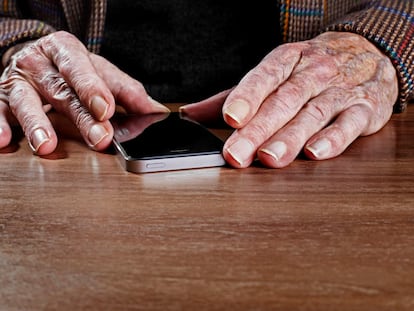 Las manos de una persona mayor sujetan un móvil.