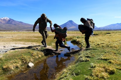 Un soldado chileno ayuda a migrantes a cruzar un canal de agua cerca de Colchane, Chile, en marzo de 2023.