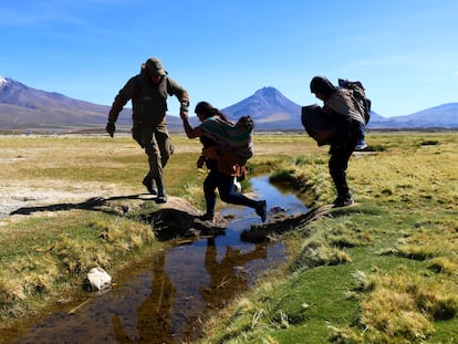 Un soldado chileno ayuda a migrantes a cruzar un canal de agua cerca de Colchane, Chile, en marzo de 2023.